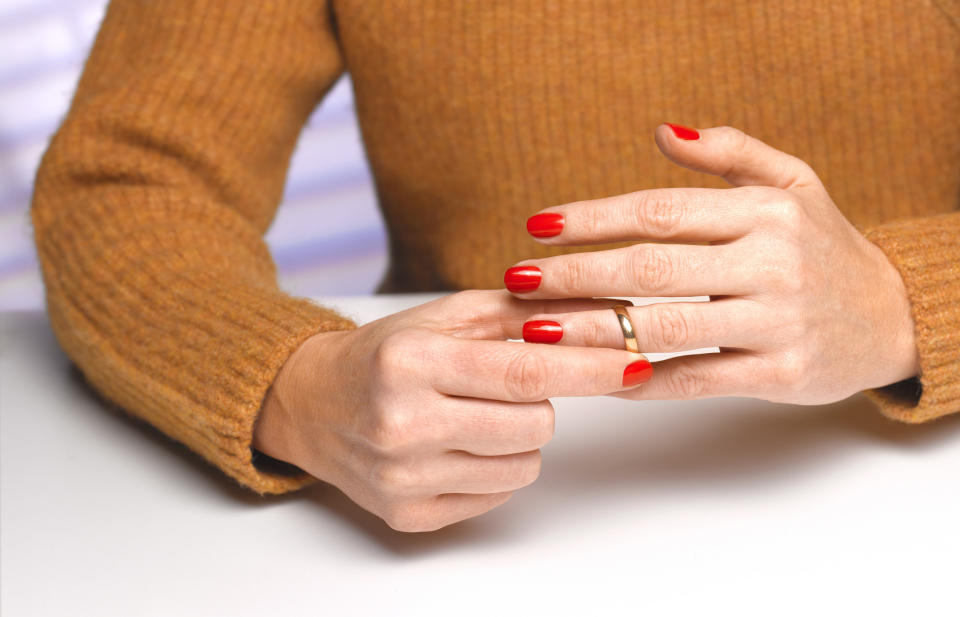 hands taking off a wedding ring