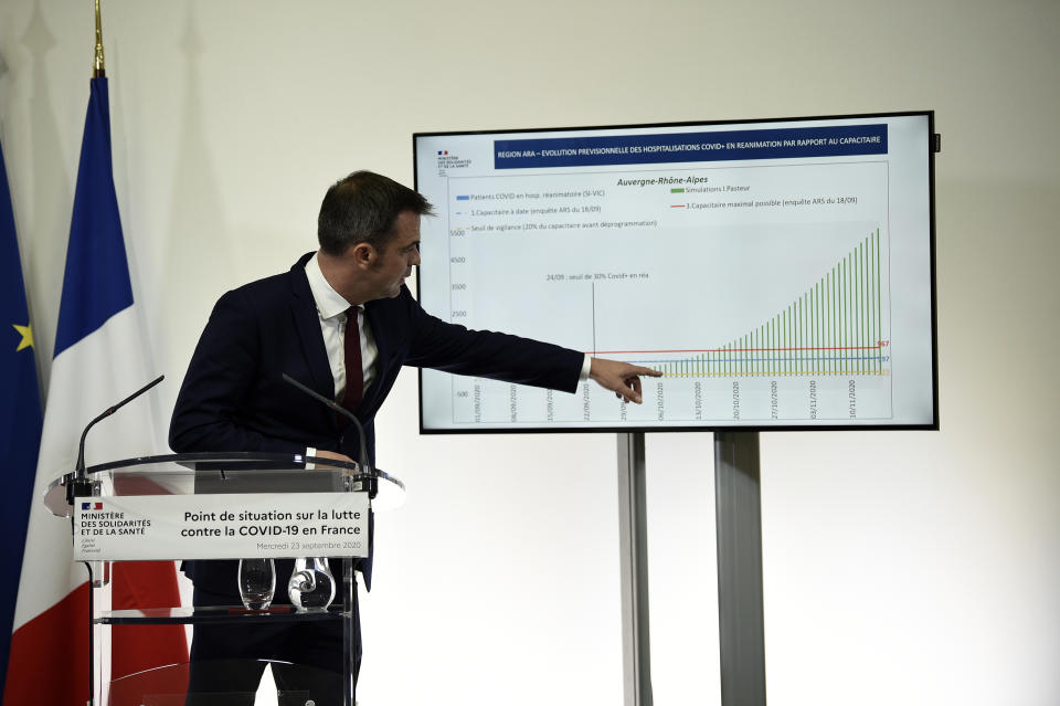 French Health Minister Olivier Veran points to a graphic on the virus situation in central France during a press conference in Paris, Wednesday Sept. 23, 2020. French Health Minister Olivier Veran announced the closure of all restaurants and bars in the Marseille region and restrictions across a dozen other cities to stem the resurgent spread of the virus. With COVID-19 patients now occupying more than 10% of France's intensive care beds, Veran stopped short of imposing new lockdowns, but urged people to resume working from home and stop gathering with big groups of family and friends. (Eliot Blondet/Pool via AP)