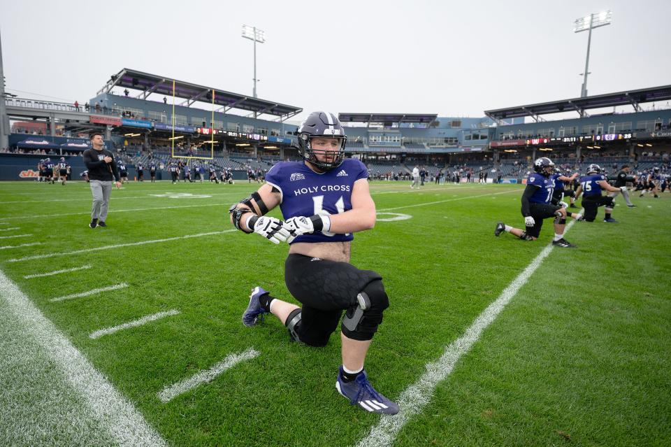 Holy Cross offensive lineman Cam Nolan of Oxford stretches before Saturday's game against Harvard at Polar Park.