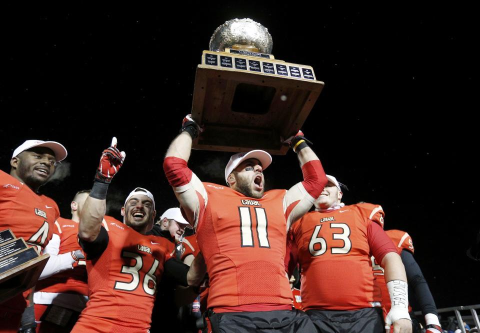 Laval Rouge et Or players Guillaume Rioux (11), Pascal Lochard (L), Vincent Plante (36) and Pierre Lavertu (R) celebrate with the trophy after defeating the Calgary Dinos to win the Vanier Cup University Championship football game in Quebec City, Quebec, November 23, 2013. REUTERS/Mathieu Belanger (CANADA - Tags: SPORT FOOTBALL)