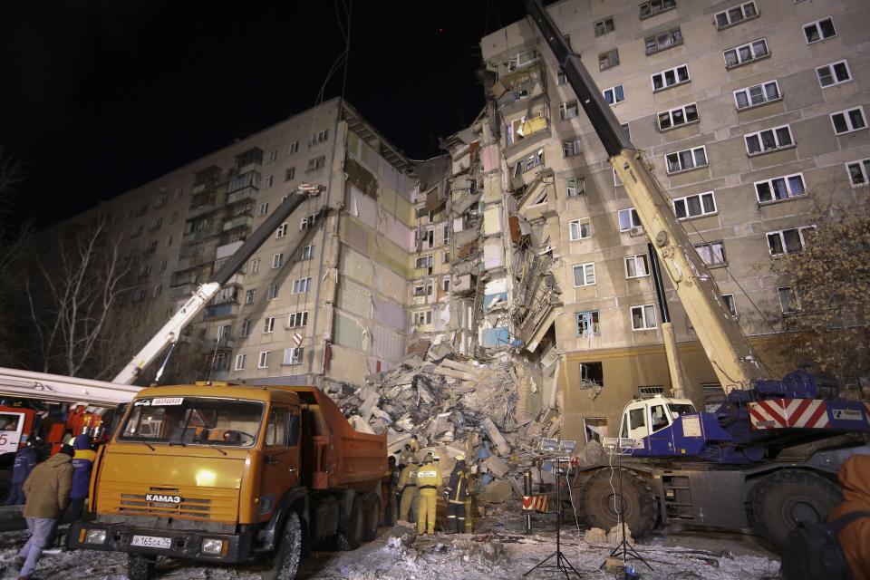 Emergency Situations employees working at the scene of a collapsed apartment building in Magnitogorsk, a city of 400,000 people, about 1,400 kilometers (870 miles) southeast of Moscow, Russia, Monday, Dec. 31, 2018. At least four people died Monday when part of a 10-story apartment building collapsed in Russia's Ural Mountains region, and hundreds of rescuers searched for survivors under the rubble in the frigid weather. (AP Photo/Maxim Shmakov)