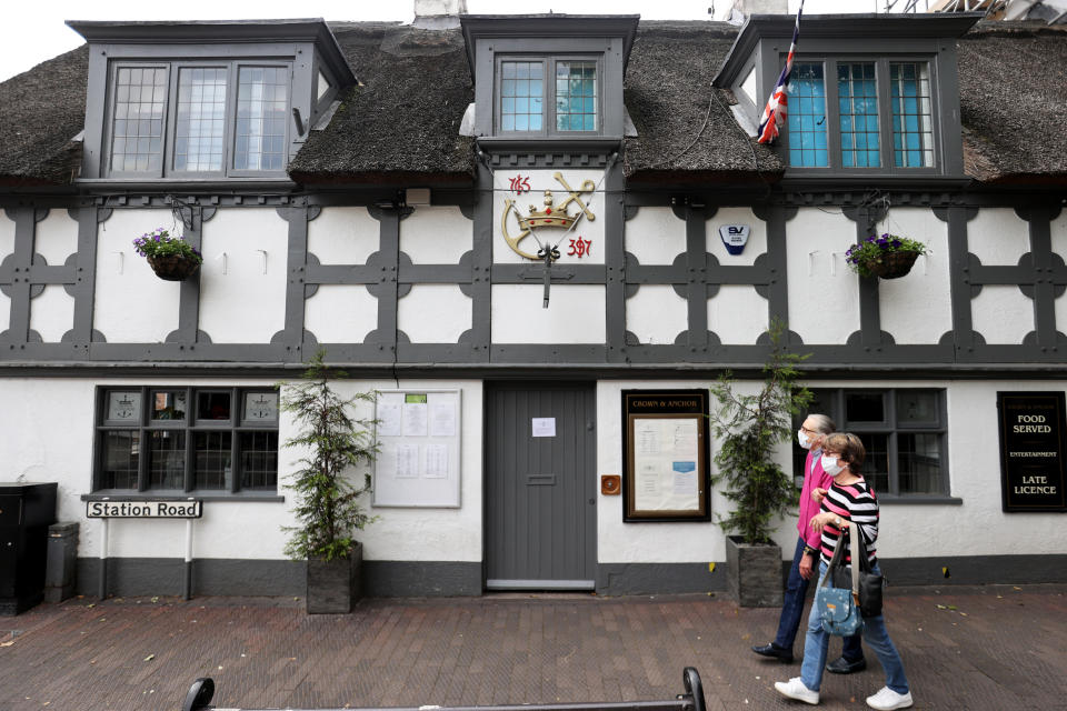 People wearing face masks walk past the Crown and Anchor pub following a spike in cases of the coronavirus disease (COVID-19) to visitors of the pub in Stone, Britain, July 29, 2020. REUTERS/Carl Recine