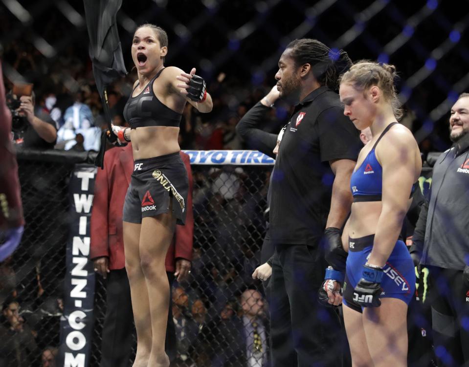 Amanda Nunes, left, celebrates her win as Ronda Rousey stands at right, after their women's bantamweight championship mixed martial arts bout was stopped in the first round at UFC 207, Friday, Dec. 30, 2016, in Las Vegas. (AP Photo/John Locher)
