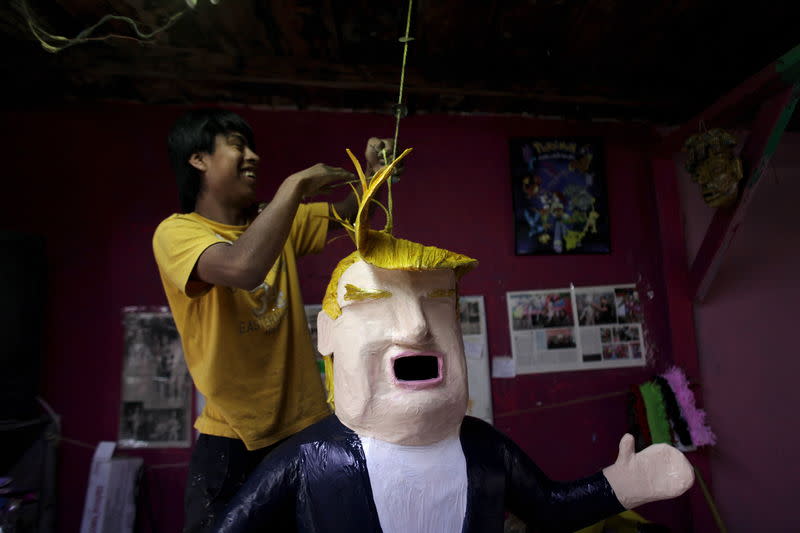 A worker hangs a pinata depicting U.S. Republican presidential candidate Donald Trump at a workshop in Reynosa, Mexico, June 23, 2015.  REUTERS/Daniel Becerril<br class=