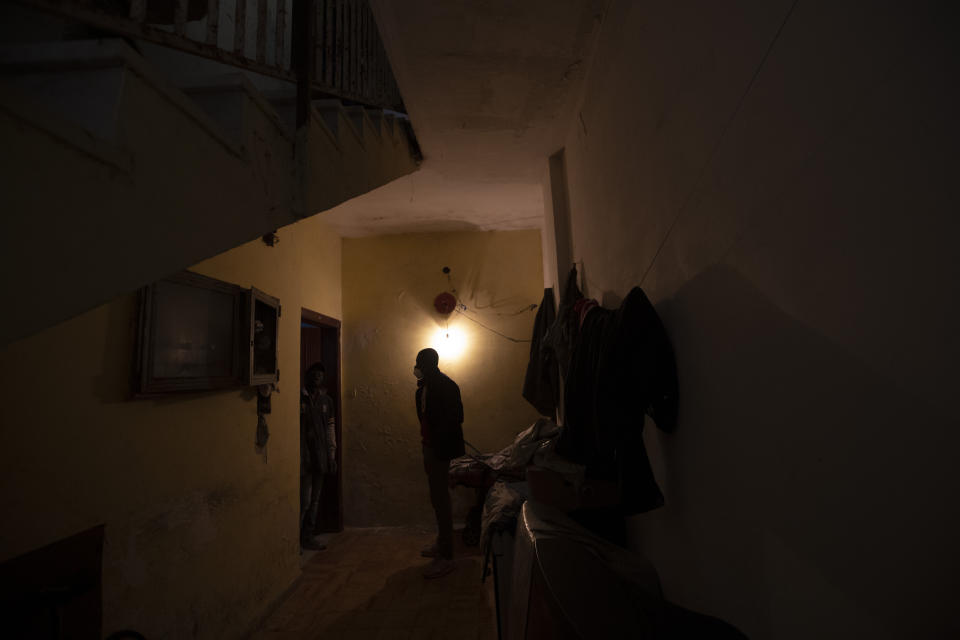 In this photo taken on Monday, April 27, 2020, Appiah Kwasi, a cultural mediator from Ghana, enters the house where Jimmy Donko, 43 from Ghana, lives with other 45 men, from Nigeria and Ghana, in Castel Volturno, near Naples, Southern Italy. The home has no running water, the dilapidated electrical system doesn't reach many rooms that are in the dark. They are known as “the invisibles,” the undocumented African migrants who, even before the coronavirus outbreak plunged Italy into crisis, barely scraped by as day laborers, prostitutes and seasonal farm hands. Locked down for two months in their overcrowded apartments, their hand-to-mouth existence has grown even more precarious with no work, no food and no hope. (AP Photo/Alessandra Tarantino)