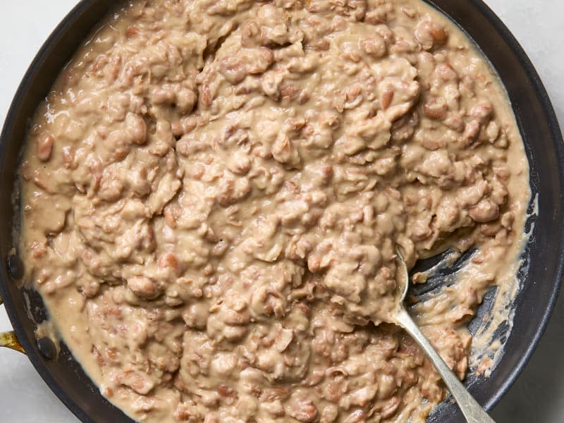 An overhead view of refried beans in a cast iron skillet.