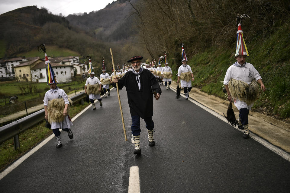 In this Monday, Jan. 27, 2020 photo, a group of ''Joaldunak'' march along the road as they take part in a Carnival in the small Pyrenee village of Zubieta, northern Spain. In one of the most ancient carnival celebrations in Europe, dozens of people don sheepskins, lace petticoats and conical caps and sling cowbells across their lower backs as they parade to herald the advent of spring. (AP Photo/Alvaro Barrientos)