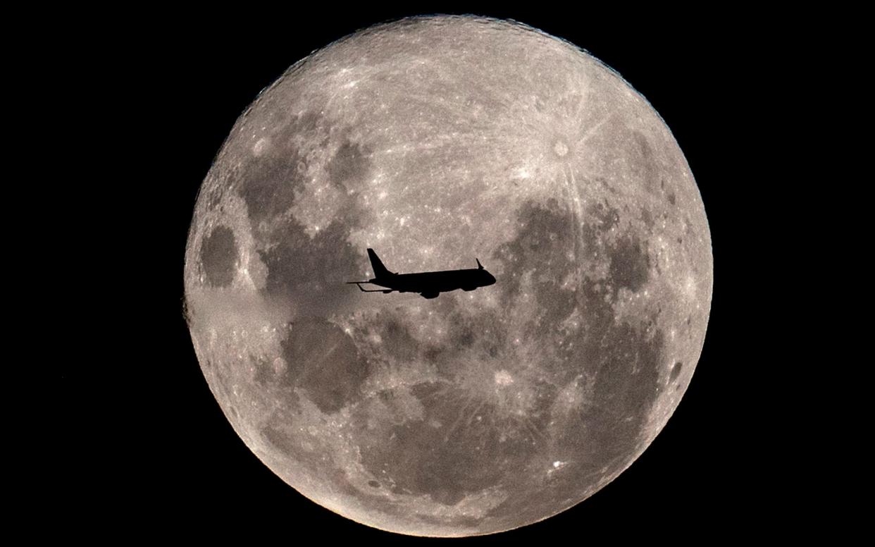 A plane passes in front of the super full moon, as seen from Buenos Aires on February 19, 2019 - AFP