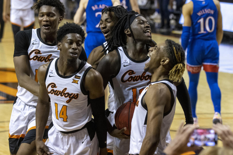 Oklahoma State's Matthew-Alexander Moncrieffe, from left to right, Bryce Williams, Kalib Boone, Isaac Likekele and Rondel Walker celebrate after the NCAA college basketball game against Kansas in Stillwater, Okla., Tuesday, Jan. 12, 2021. Oklahoma State won 75-70. (AP Photo/Mitch Alcala)
