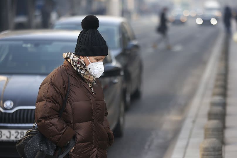 A woman wears a face mask shrouded by pollution haze as smog covers Sarajevo, Bosnia, Wednesday 20 Dec 2023