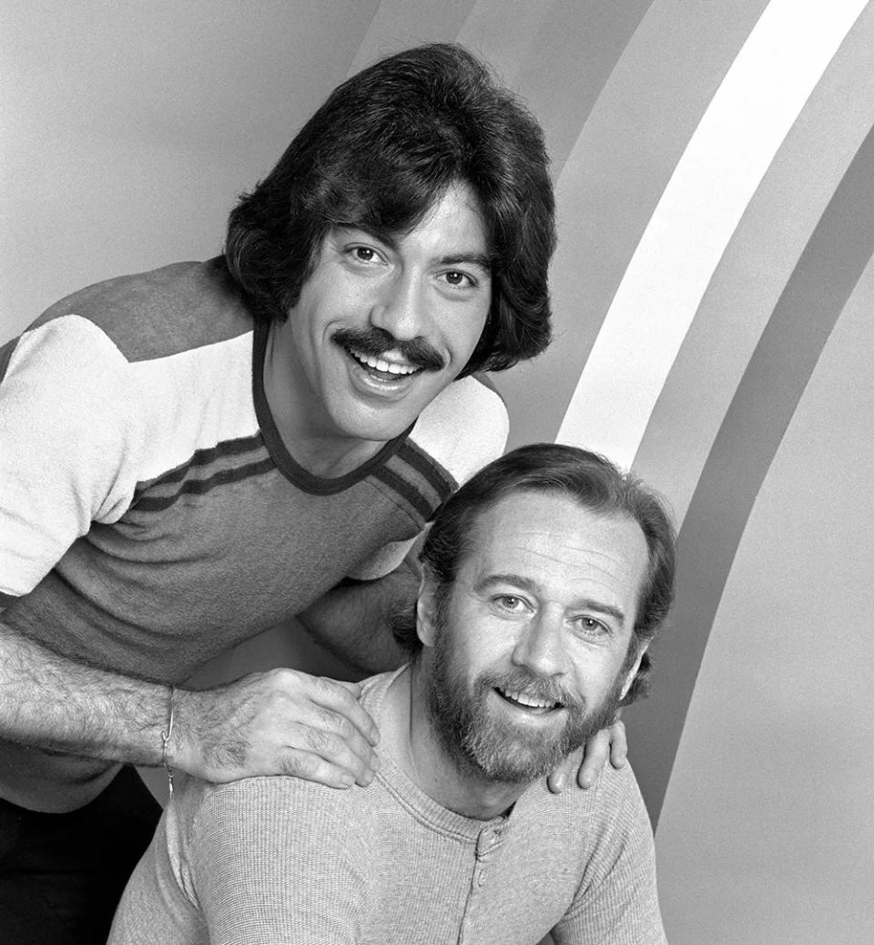 Tony Orlando standing behind George Carlin with his hands on Carlins shoulders