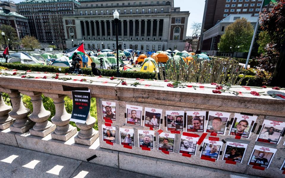 A wall with Hamas hostage flyers posted in front of the pro-Palestine encampment on campus