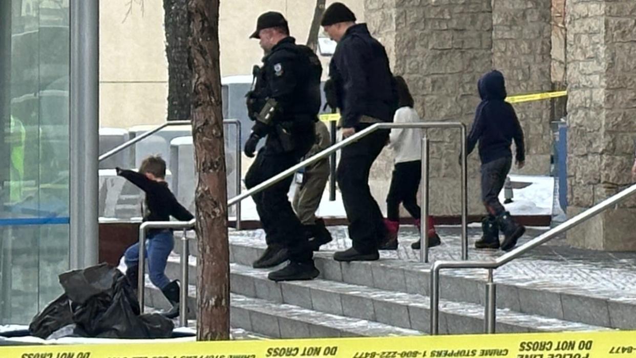 Police and children leaving Edmonton city hall after a security incident. Police say a man has been arrested after shots were fired and a Molotov cocktail was thrown in Edmonton's city hall Tuesday morning (Paige Parsons/CBC - image credit)