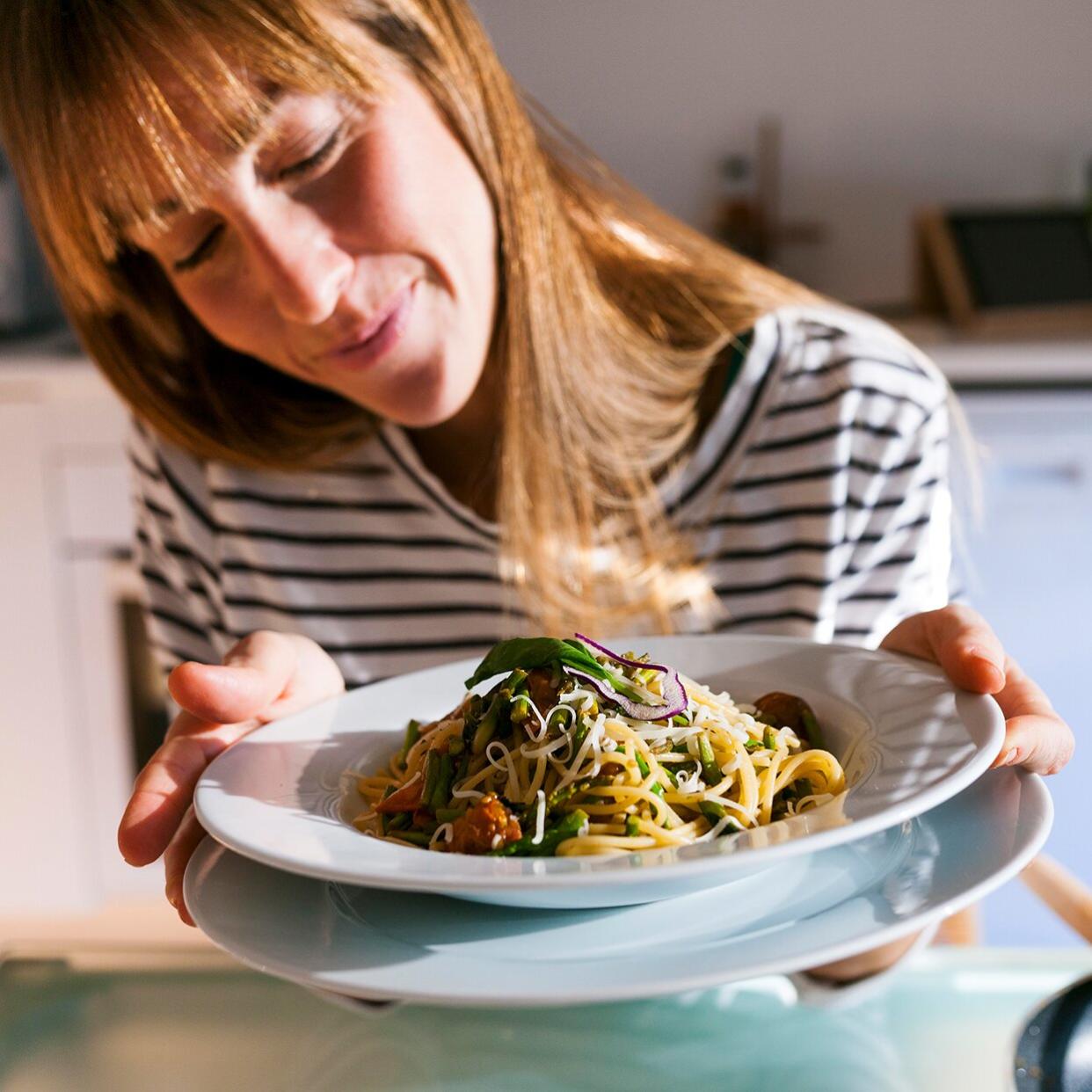 A woman cooking dinner from a plant-based meal delivery service