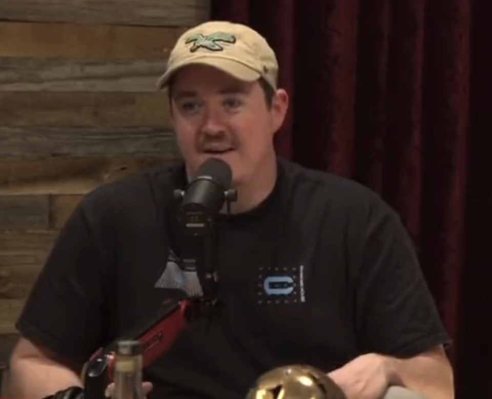 Shane in a cap sitting with a microphone in a podcast setting