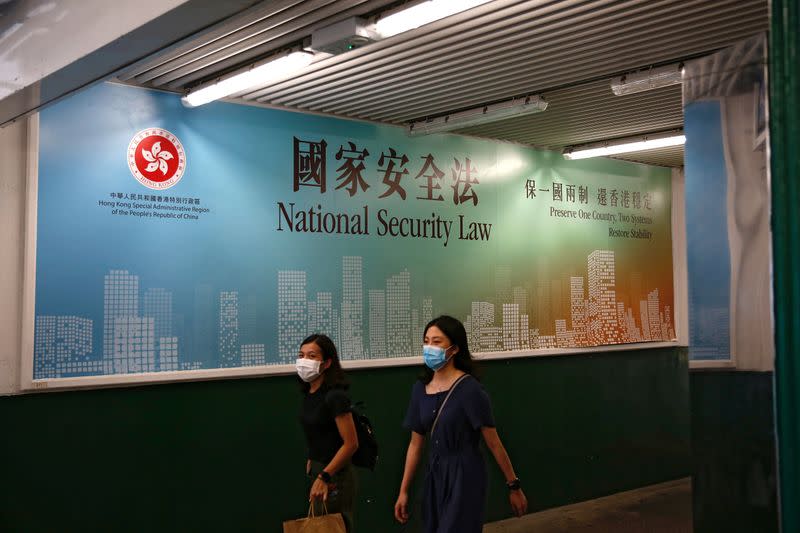 FILE PHOTO: Women walk past a government-sponsored advertisement promoting the new national security law as a meeting on national security legislation takes place in in Hong Kong