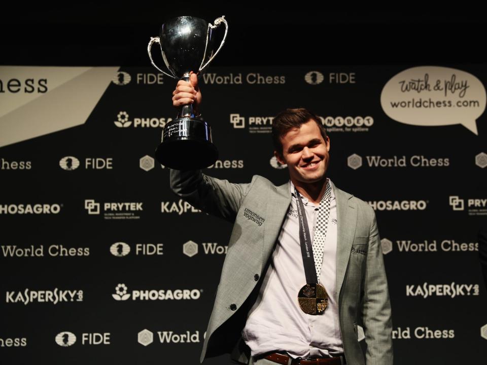 Magnus Carlsen holds up a trophy after winning the chess world championship in 2018.