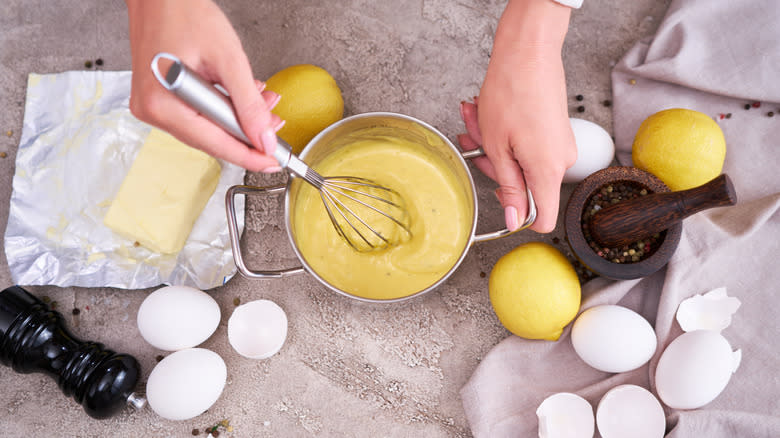 hands whisking yellow sauce