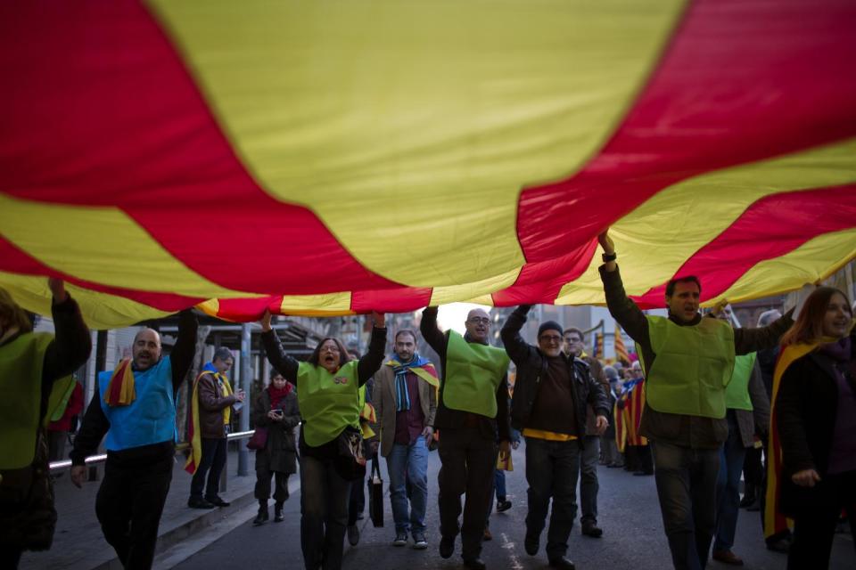 In this photo taken on Sunday, Jan. 12, 2014, people hold a huge "estelada" flag during a pro-independence event in Barcelona, Spain. After years of mass protests by Catalans demanding the right to decide whether they want to break away from Spain and form a new European nation, the wealthy northeastern region’s lawmakers vote to ask permission from Spanish authorities to hold a secession referendum in November. The request eight months ahead of a Scottish independence referendum is certain to be denied by the central government in Madrid but is virtually guaranteed of generating even more separatist fervor. (AP Photo/Emilio Morenatti)