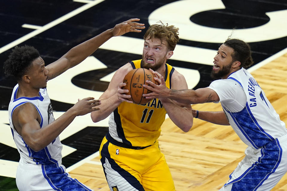 Indiana Pacers forward Domantas Sabonis (11) looks for a shot as he is defended by Orlando Magic center Wendell Carter Jr., left, and guard Michael Carter-Williams, right, during the second half of an NBA basketball game, Friday, April 9, 2021, in Orlando, Fla. (AP Photo/John Raoux)