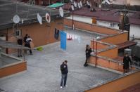 People listen to the music, as DJ Francesco Cellini play for them from the rooftop terrace, as Italians remain under lockdown to prevent the spread of coronavirus disease (COVID-19) in Monteverde district, Rome