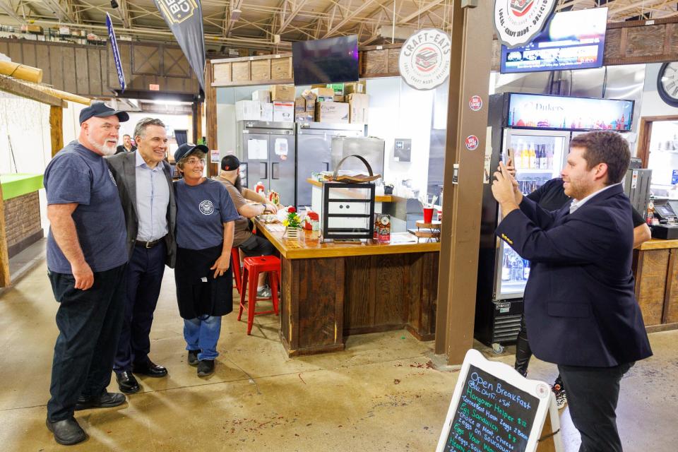 Republican Senate candidate Dave McCormick (center) poses for a photograph with John Schmidt, left, and Ingrid Schmidt, right, owners of Craft Eats, during a tour of the Markets at Hanover, Wednesday, May 8, 2024, in Penn Township. McCormick and John Schmidt worked together in previous careers, McCormick shared.