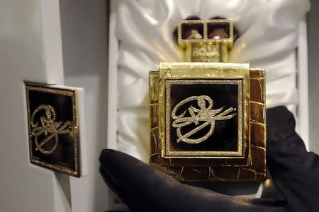 An employee poses with an exclusive single edition perfume by Roja Dove on sale for 75,000 pounds ($117,877) at the Salon de Parfums in Harrods, London, December 9, 2014. REUTERS/Luke MacGregor