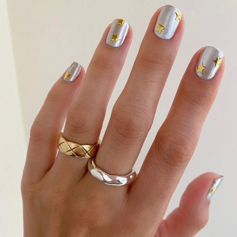 Silver and gold know no single season, but we're loving the combination of both for a fun fall manicure like <a href="https://www.instagram.com/p/CJRNKH5MWUp/?utm_medium=copy_link" rel="nofollow noopener" target="_blank" data-ylk="slk:this one by Goldstein;elm:context_link;itc:0;sec:content-canvas" class="link ">this one by Goldstein</a>. Any opaque silver polish will do for the base — Essie's <a href="https://shop-links.co/1749001493144557682" rel="nofollow noopener" target="_blank" data-ylk="slk:No Place Like Chrome;elm:context_link;itc:0;sec:content-canvas" class="link ">No Place Like Chrome</a> is a great pick — and any opaque golden polish will work for the stars. But if you don't trust your hand to be steady enough to paint on perfect stars, you can always <a href="https://www.amazon.com/Sheets-Crowns-Stars-Vines-Stickers/dp/B07667Z85J" rel="nofollow noopener" target="_blank" data-ylk="slk:try decals;elm:context_link;itc:0;sec:content-canvas" class="link ">try decals</a> to make it especially easy to achieve this look.