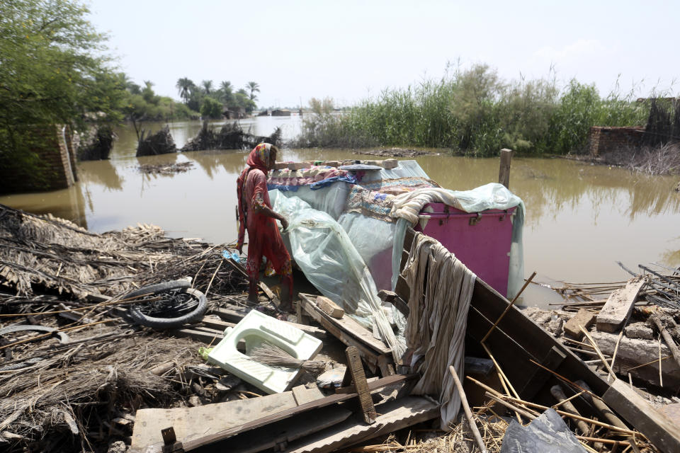 Muktiyara Bibi looks for salvageable belongings from her flood-hit home in Shikarpur district of Sindh province, of Pakistan, Tuesday, Aug. 30, 2022. Disaster officials say nearly a half million people in Pakistan are crowded into camps after losing their homes in widespread flooding caused by unprecedented monsoon rains in recent weeks. (AP Photo/Fareed Khan)