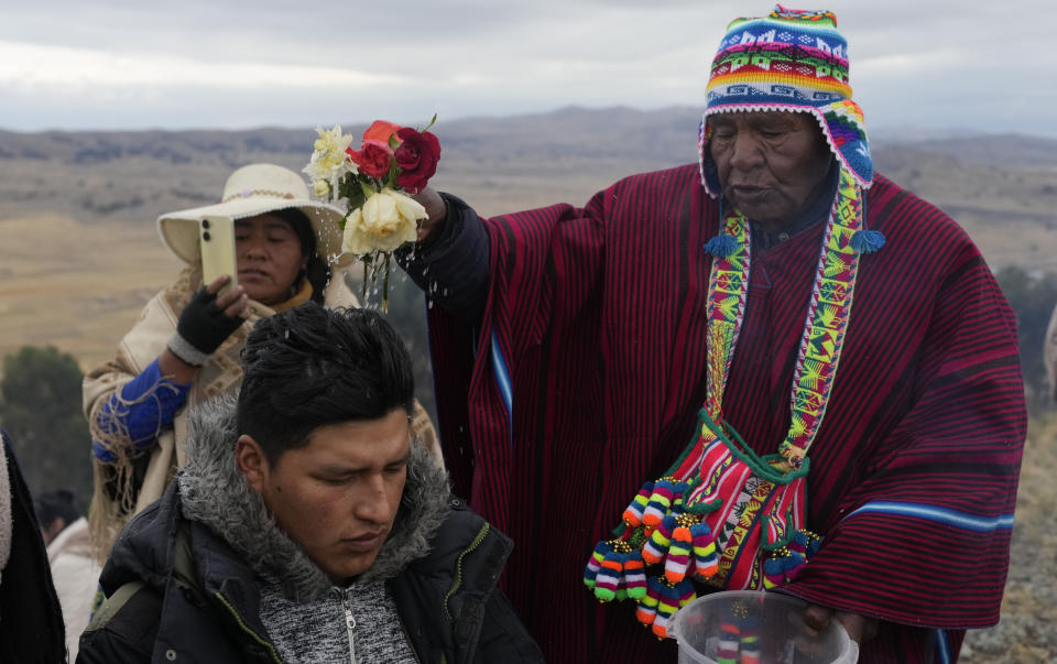 El líder espiritual José Mamani bendice a una persona con agua en un ritual por el Año Nuevo Andino tras recibir los primeros rayos de sol del día en el cerro Turriturrini a las afueras de Huarina, Bolivia, el viernes 21 de junio de June 21, 2024. Comunidades indígenas aymaras celebran el año nuevo 5.532 o el "Willka Kuti" que significa "Regreso del Sol" en aymara. (AP Foto/Juan Karita)