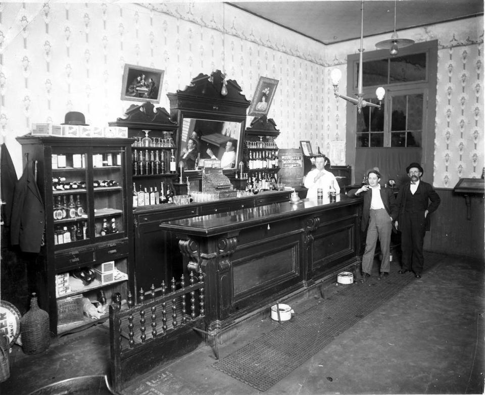 Undated circa 1910s photo in an unidentified San Luis Obispo saloon photo printed from a glass plate. Cigars labeled San Luis Perfectos are under a bowler hat at the left. A bottle cap calendar on the wall shows this was a day in a leap year February. Gas lamps are lit, electric lamps are not. Dignified women were rarely seen in bars before prohibition.