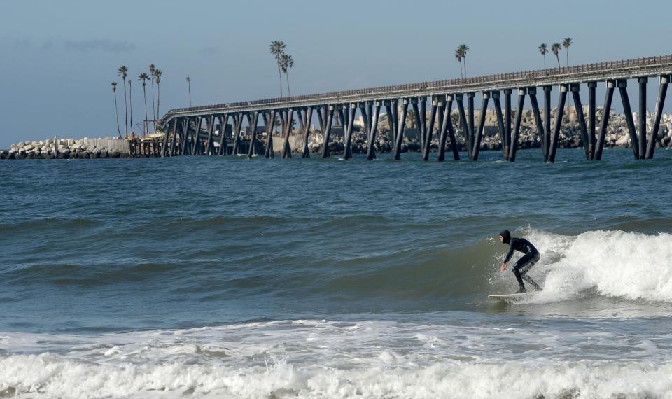 A surfer catches a wave near Rincon Island, just off the coast of Mussel Shoals, in this file photo. The state of California paid tens of millions of dollars to plug and abandon the island's oil wells after the operator, Rincon Island Limited Partnership, filed for bankruptcy protection.