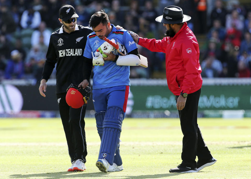 New Zealand's Kane Williamson, left and Umpire Aleem Dar check that Afghanistan's Rashid Khan is ok, after a ball bowled by Lockie Ferguson bounced off Rashid's helmet and onto the stump during the ICC Cricket World Cup group stage match between Afghanistan and New Zeland, at the County Ground Taunton, England, Saturday, June 8, 2019. (Mark Kerton/PA via AP)