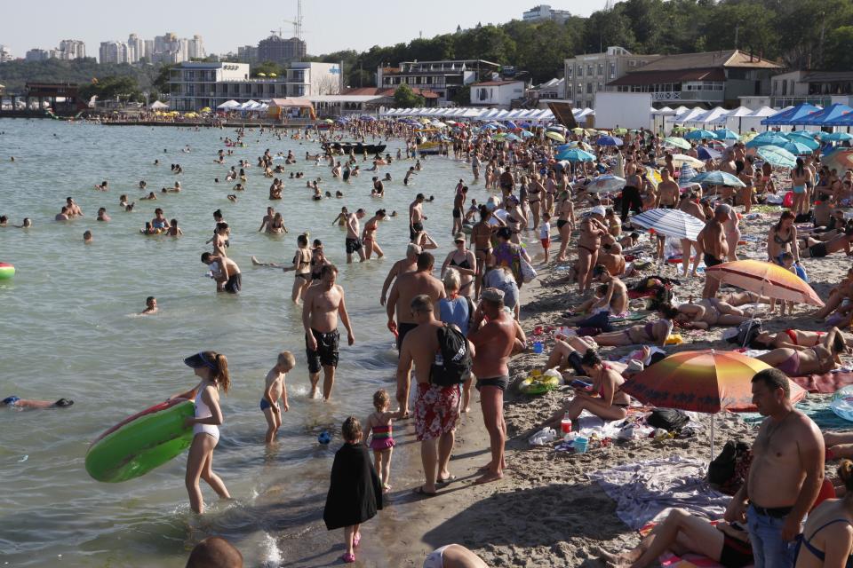 People enjoy the beach in the Black Sea in Odessa, Ukraine, Saturday, July 4, 2020. Tens of thousands of vacation-goers in Russia and Ukraine have descended on Black Sea beaches, paying little attention to safety measures despite levels of contagion still remaining high in both countries. (AP Photo/Sergei Poliakov)