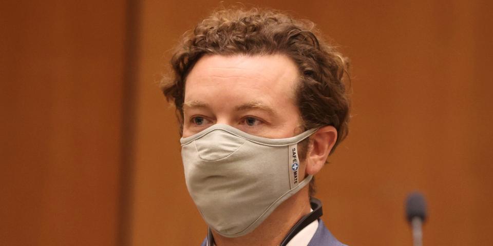 Danny Masterson stands in court with a mask on his face.