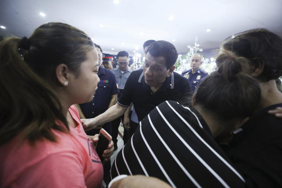 In this photo provided by the Presidential Malacanang Palace on Saturday July 20, 2019, Philippine President Rodrigo Duterte comforts relatives of slain police officers during his visit to their wake at Camp Lt. Col. Francisco C. Fernandez Jr. in Sibulan, Negros Oriental, in Central Philippines. On Thursday, July 25, 2019, President Rodrigo Duterte said he raised a reward of 3 million pesos ($59,000) out of anger for what he described as the Islamic State group-style killings of the officers on July 18 in Negros Oriental province. Communist guerrillas claimed responsibility for the attack but denied torturing the police officers. (Ace Morandante/Presidential Photo Via AP)