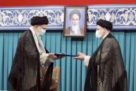 In this photo released by an official website of the office of the Iranian supreme leader, Supreme Leader Ayatollah Ali Khamenei, left, gives his official seal of approval to newly elected President Ebrahim Raisi in an endorsement ceremony in Tehran, Iran, Tuesday, Aug. 3, 2021. A portrait of the late revolutionary founder Ayatollah Khomeini hangs in the background. (Office of the Iranian Supreme Leader via AP)