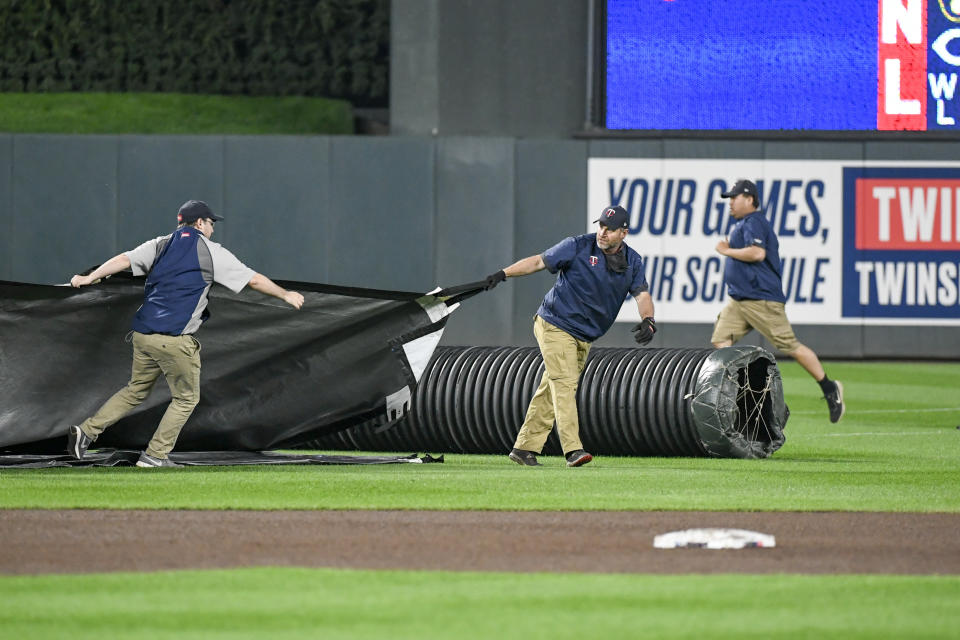 Members of the ground crew quickly pull out the tarp as the game between the Minnesota Twins and Houston Astros is delayed because of thunderstorms and tornado warnings during the third inning of a baseball game, Wednesday, May 11, 2022, in Minneapolis. (AP Photo/Craig Lassig)