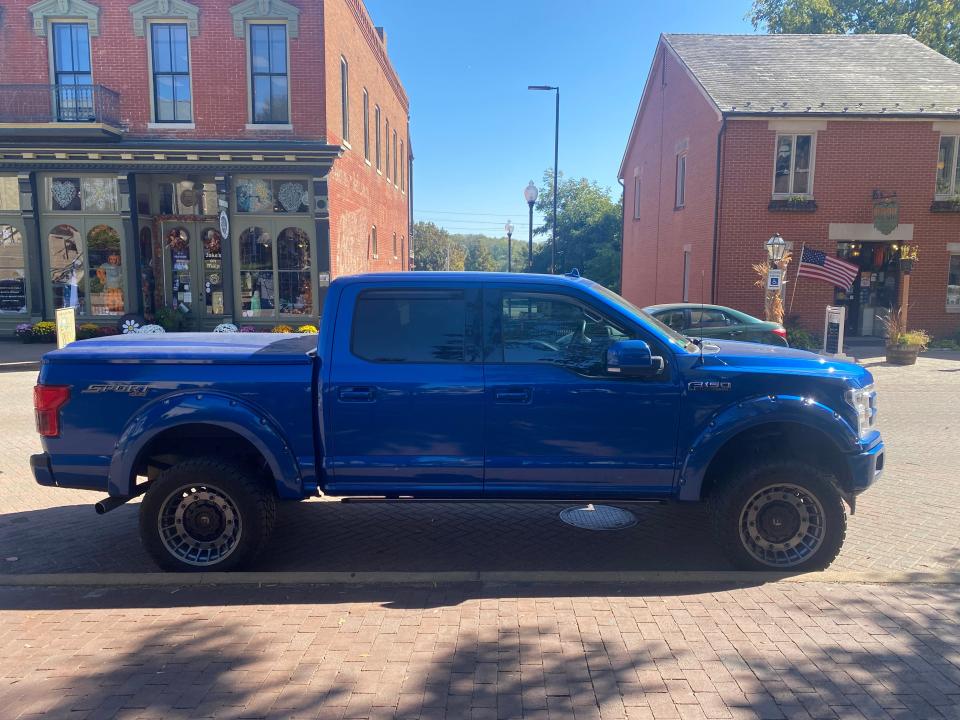 blue pickup truck parked on a street in a small american town