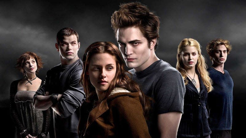 Jacob holds Bella from behind in front of some vampires.