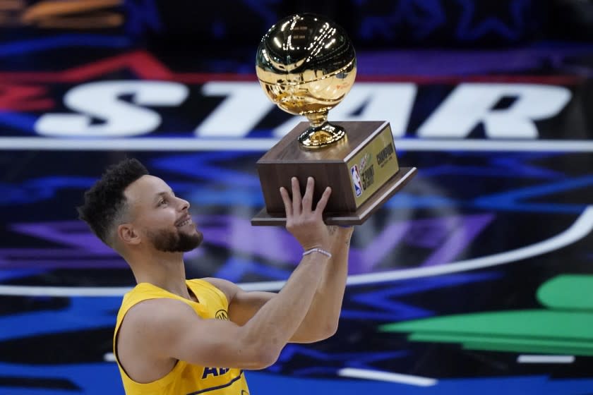 Golden State Warriors guard Stephen Curry holds the trophy after winning the 3-point contest.