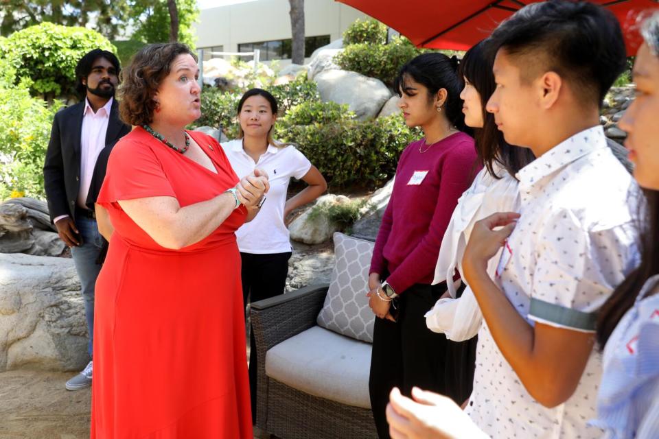 Katie Porter standing in an outdoor area, talking with several young people