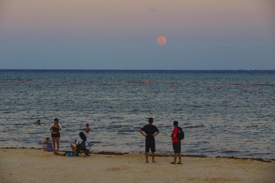 Tourists watch the lunar eclipse and blood moon in Parque Fundadores, this astronomical phenomenon is the first lunar eclipse of the year known as a super moon because the moon is closer to the earth. On May 15, 2022 in Playa del Carmen, Mexico.  / Credit: (Natalia Pescador/Getty Images)