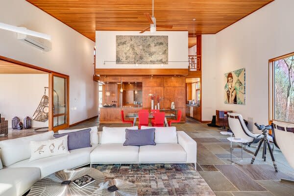 Stone flooring connects the main living spaces located on the ground level. Beyond the dining area is a large, open chef's kitchen, fitted with top-of-the-line appliances.