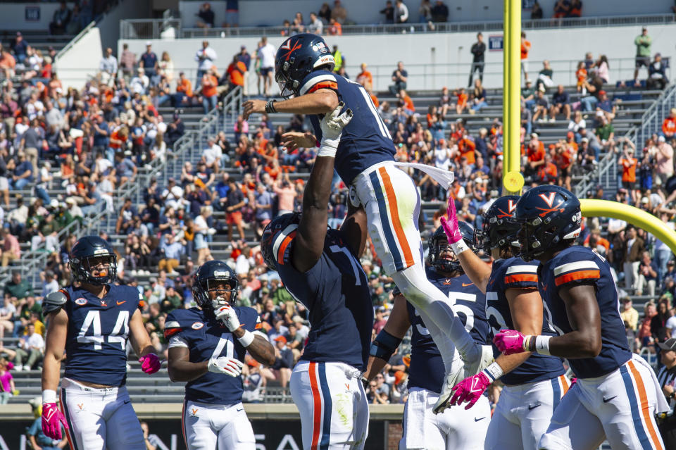 Virginia quarterback Tony Muskett (11) is lifted in the air by teammate Ugonna Nnanna (71) as they celebrate a touchdown against William & Mary during the first half of an NCAA college football game Saturday, Oct. 7, 2023, in Charlottesville, Va. (AP Photo/Mike Caudill)