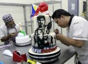 A cake decorator puts finishing touches to a two-layer cake featuring boxer Manny Pacquiao of the Philippines at a bakery in Manila May 1, 2015. REUTERS/Romeo Ranoco