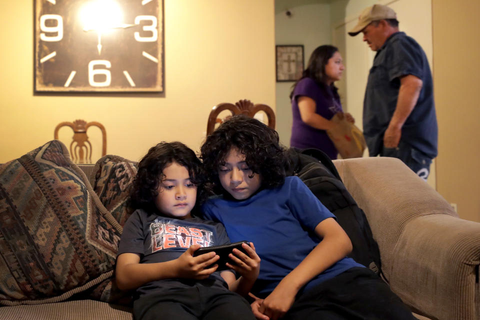 Joseph Diaz, 10, right, and his brother, John Diaz, 7, watch videos as their parents, Karina Ruiz and Humberto Diaz prepare dinner at their home, Thursday, Nov. 7, 2019 in Glendale, Ariz. Karina is in a program dating back to the Obama administration that allows immigrants brought here as children to work and protects them from deportation. The U.S. Supreme Court will hear arguments Tuesday, Nov. 12, about President Donald Trump’s attempt to end the program, and the stakes are particularly high for the older generation of people enrolled in Deferred Action for Childhood Arrivals, known as DACA.(AP Photo/Matt York)