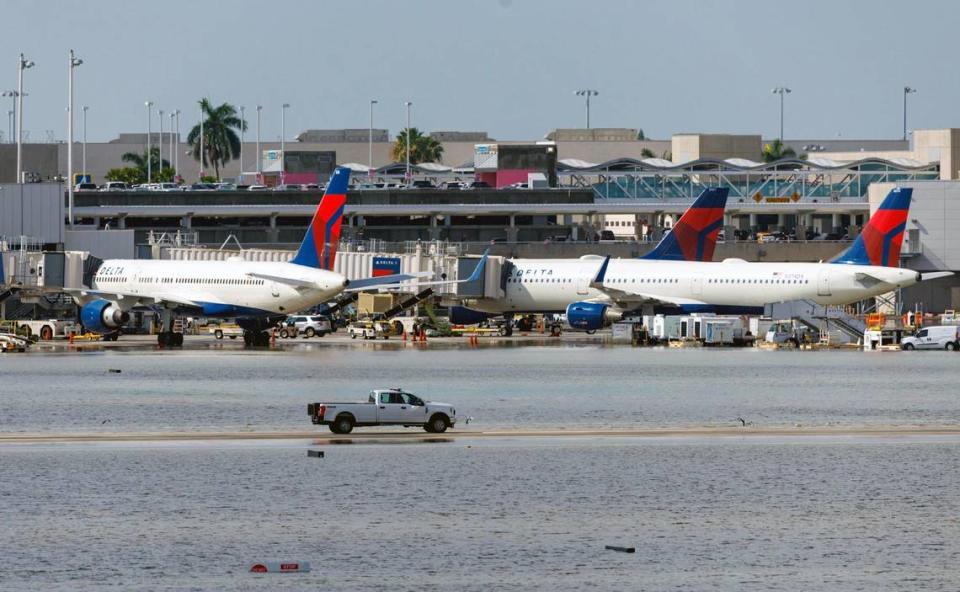 Delta Air Lines airplanes at their terminal as a truck drives through the flooded tarmac at the Fort Lauderdale-Hollywood International Airport on Thursday, April 13, 2023.