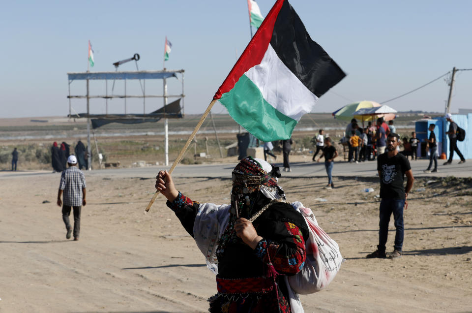 In this Sept. 25, 2019 photo, a Palestinian woman waves a national flag during a alternative protest organized by activist Ahmed Abu Artima near the separation fence between the Gaza Strip and Israel, east of Gaza City. Gaza’s Hamas rulers are facing a rare and growing chorus of criticism, with little to show after 18 months of mass protests along the Israeli border organized by the Palestinian militant group. Gazans are increasingly questioning the high number of casualties and lack of success in lifting the Israeli blockade. Against this backdrop, Artima has launched his own peaceful version of the protest. (AP Photo/Adel Hana)