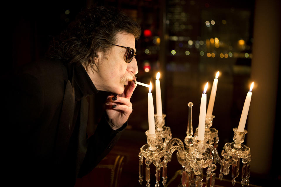 Argentine rock legend Charly Garcia lights a cigarette using a candle flame before an interview in Buenos Aires, Argentina, Wednesday, Aug. 14, 2013. Garcia, who is 61 and has a vast career that defined and inspired the rock and pop music world in Latin America, will perform two shows at Teatro Colon, Argentina's landmark opera house, on Sept. 23 and 30. (AP Photo/Victor R. Caivano)